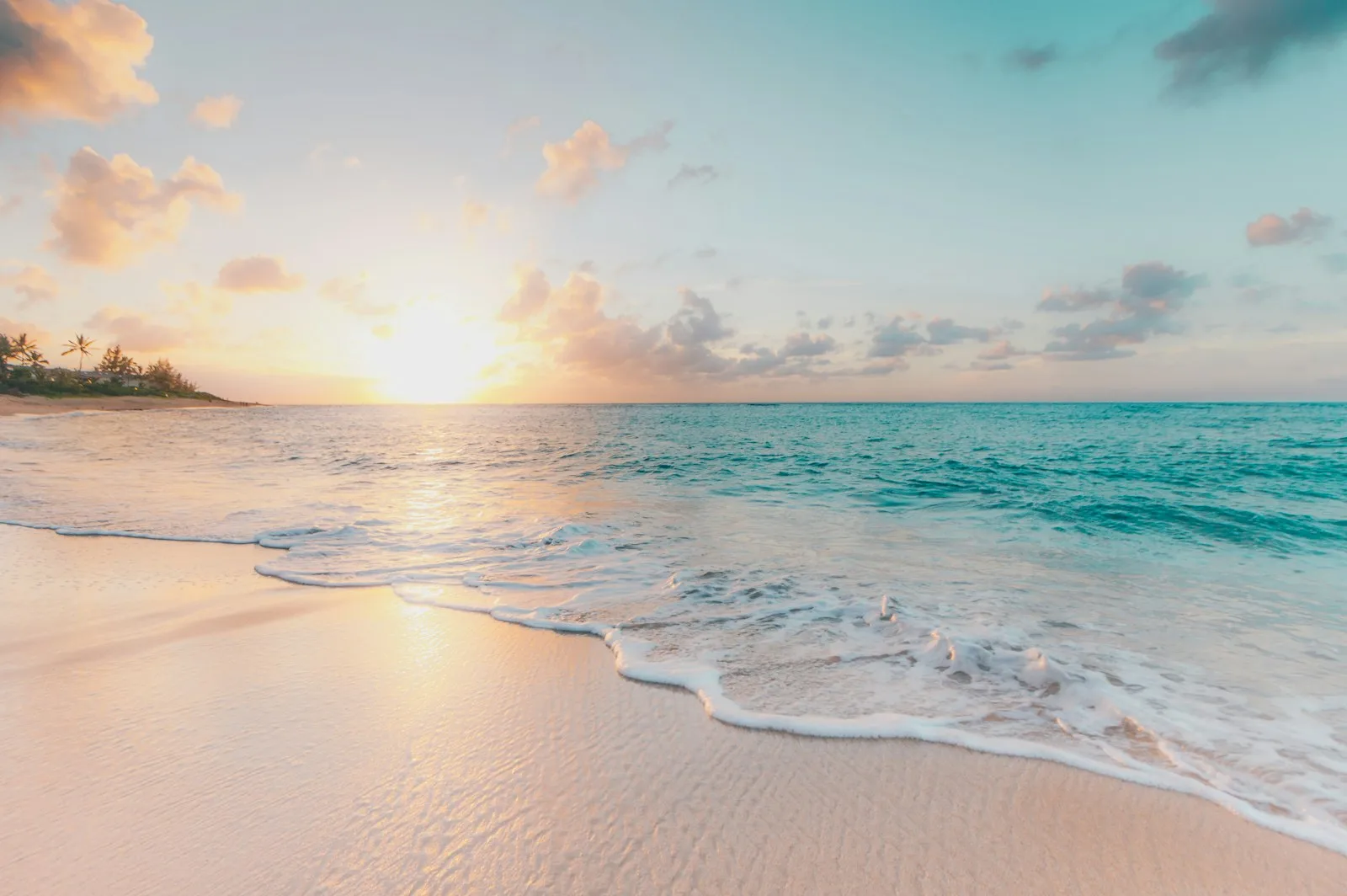 Soft white sand and turquoise waves on a sunlit tropical beach